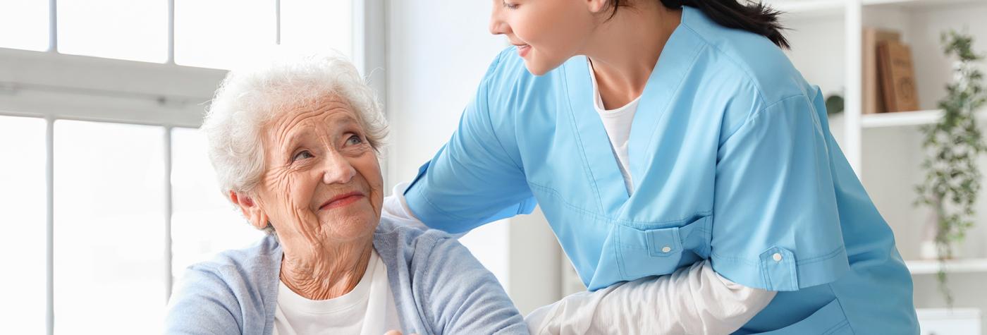 Healthcare provider helps older woman in wheelchair in her home. 