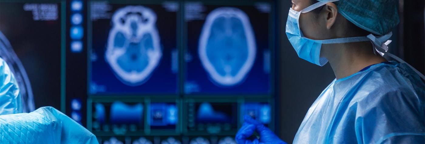 Healthcare provider looks at screen of brain scans in the operating room