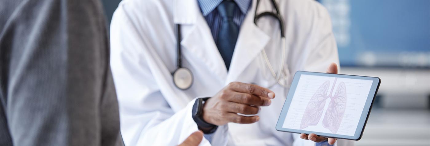 Pulmonology provider shows a patient a lung diagram on a digital tablet 