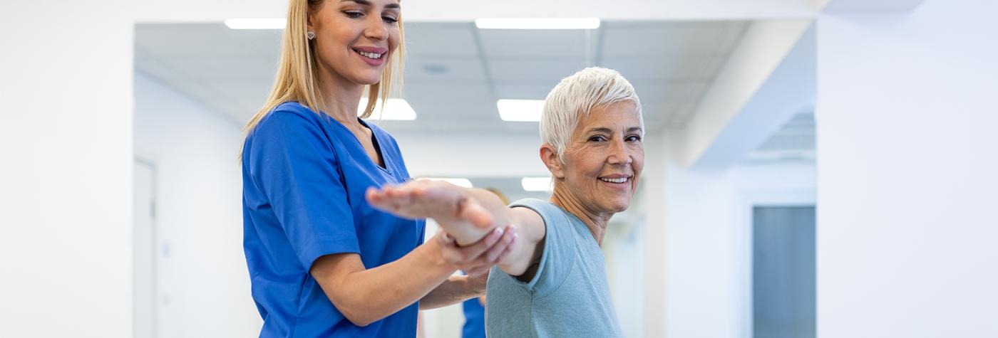 Physical therapist helps patient stretch arm 