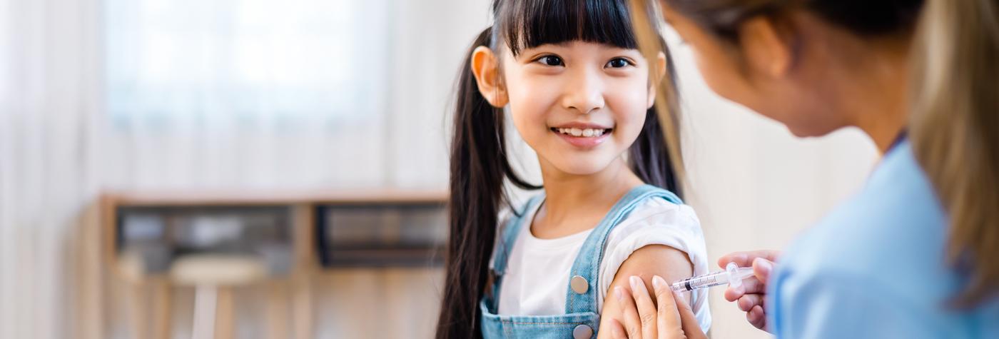 Healthcare provider gives a child an immunization in their upper arm. 