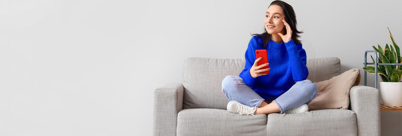 Woman sitting on couch with cell phone in hand